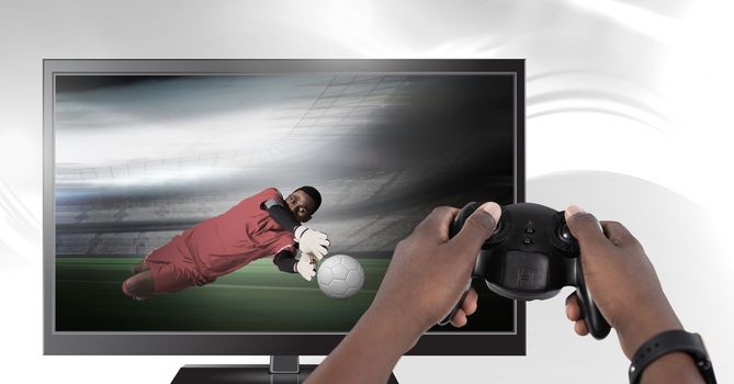 Hands holding gaming controller  with soccer player goalie on television