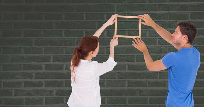 Couple holding picture frame against wall
