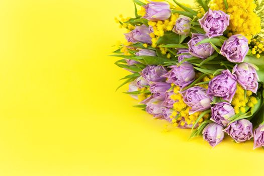 Bouquet of lilac tulips and yellow mimosas on yellow background, copy space, side view, closeup. March 8, February 14, birthday, Valentine's, Mother's, Women's day celebration, spring concept