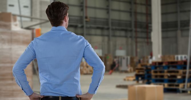 Businessman holding hands on hips in warehouse