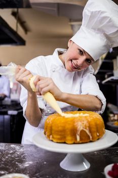 Female chef piping a cake in kitchen