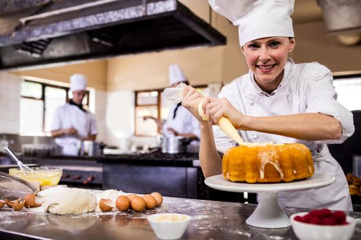 Female chef piping a cake in kitchen
