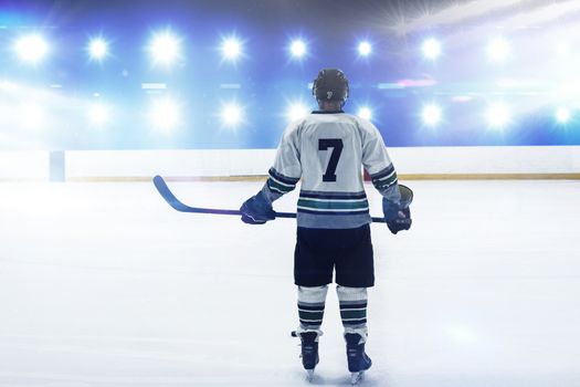 Composite image of hockey player with hockey stick standing on rink