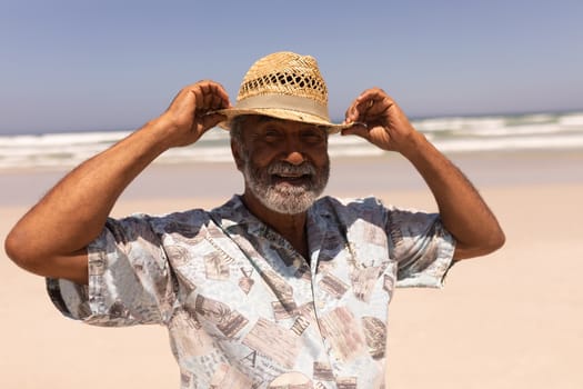 Senior black man with hat looking at camera on beach