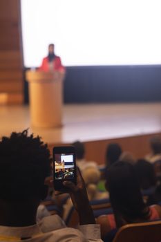  Man with smartphone taking video clip of businesswoman in the auditorium 