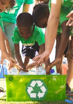 Students putting plastic bottles on dustbin in schoolyard