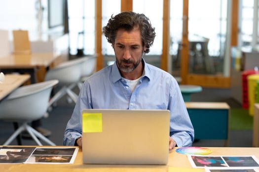 Male graphic designer using laptop at desk