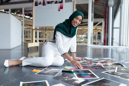 Female graphic designer in hijab checking photographs in office