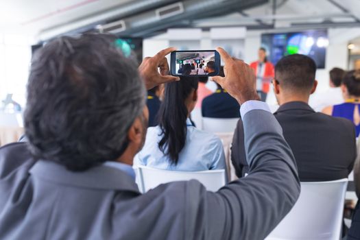 Close-up of Businessman clicking photo of business seminar with mobile phone
