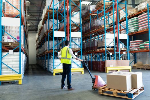 Male staff using pallet jack in warehouse