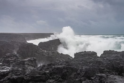 Brimketill lava rock pool in Iceland huge wave hitting black basalt coast