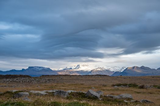 Snaefellsness national park in Iceland Snaefellsjoekull glacier in sunlight spot next to wave form clouds
