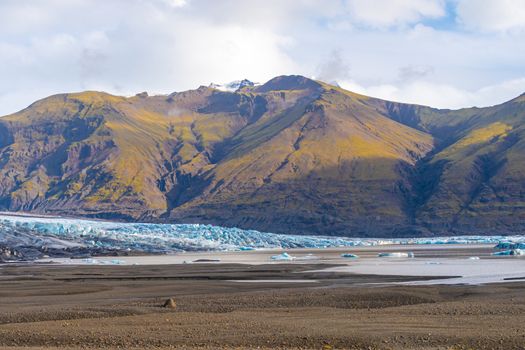 Vatnajoekull glacier in Iceland deep blue ice in front of overgrown mountains