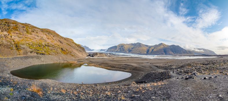 Vatnajoekull glacier in Iceland small glacier lake in front of deep blue eternal ice panorama