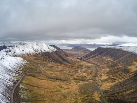 Westfjords of Iceland aerial photo of mountain pass leading down in valley beyond snow line