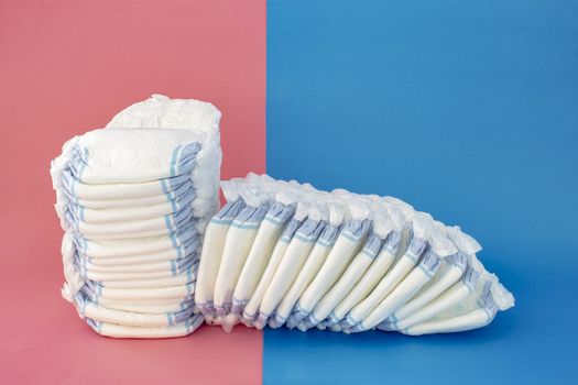 Diapers stack with some diapers falling on the right side on a blue and pink background