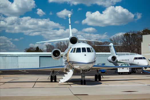 Two luxury private jets on the tarmac by hangers at a regional airport