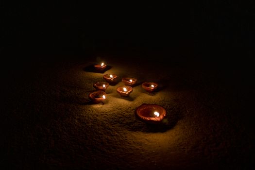 Glowing clay lamp in dark night - Happy Diwali, Light festival, Illuminated lights