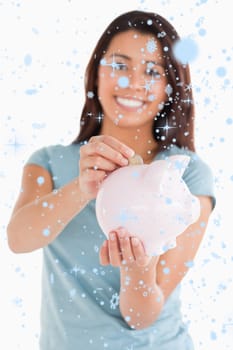 Composite image of lovely woman inserting a coin in a piggy bank