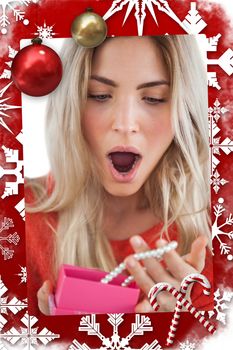 Composite image of shocked woman discovering necklace in a gift box