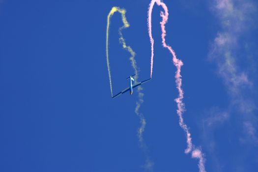 Glider performing aerobatics with smoke trails at airshow