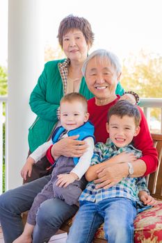 Senior Adult Chinese Couple Sitting With Their Mixed Race Grandchildren