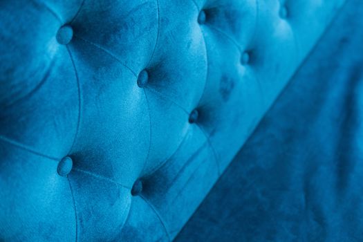 Velour surface of sofa close-up. Coach-type velours screed tightened with buttons. Blue chesterfield style quilted upholstery backdrop close up.