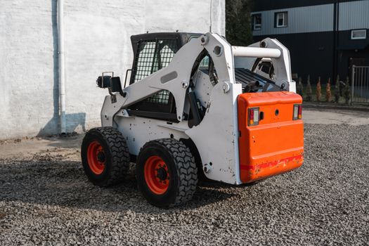 White skid steer loader at a construction site waiting of work. Industrial machinery. Industry.