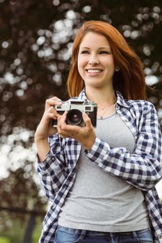 Woman wearing jeans and check shirt holding camera