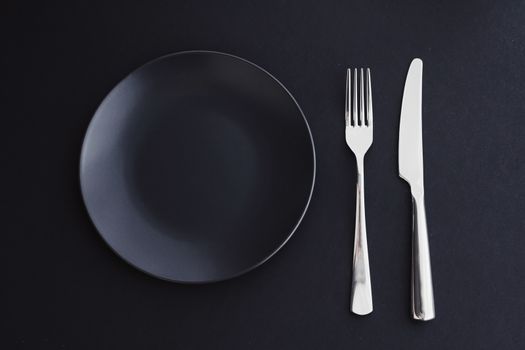 Empty plates and silverware on black background, premium tablewa
