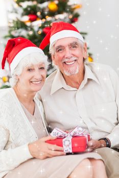 Smiling old couple swapping christmas gifts