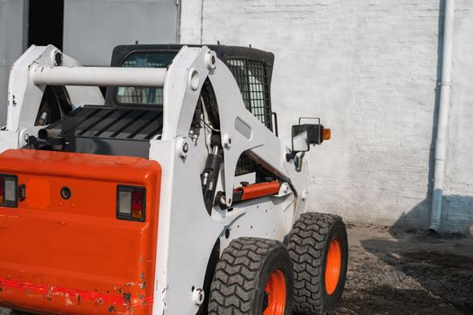 White skid steer loader at a construction site waiting of work. Industrial machinery. Industry.