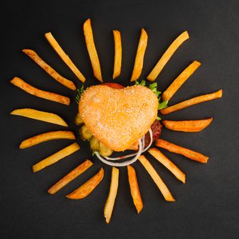 Heart shape burger cheeseburger hamburger and french fries, love fast food concept, on black background, top view flat lay
