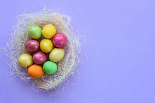 Easter eggs in a makeshift nest on a purple background