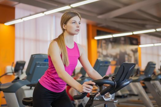 Woman doing cardio workout biking training in gym
