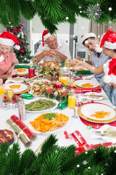 Composite image of happy family in santas hats enjoying christmas dinner