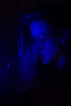 Close up portrait of vaping girl in neon blue light