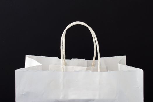 A white paper bag with holders on a black background