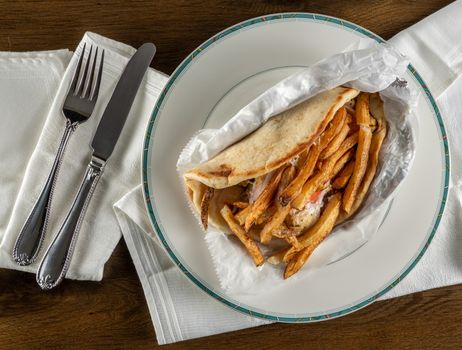 Flat lay of Greek chicken souvlaki gyro take out food arranged on plate