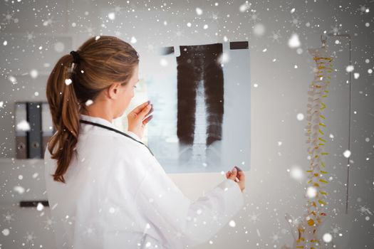 Gorgeous doctor with a stethoscope looking at a xray against snow falling
