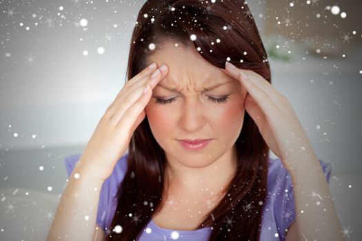 Composite image of young woman with headache at home against snow