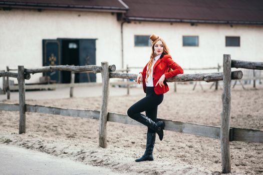 red-haired jockey girl in a red cardigan and black high boots