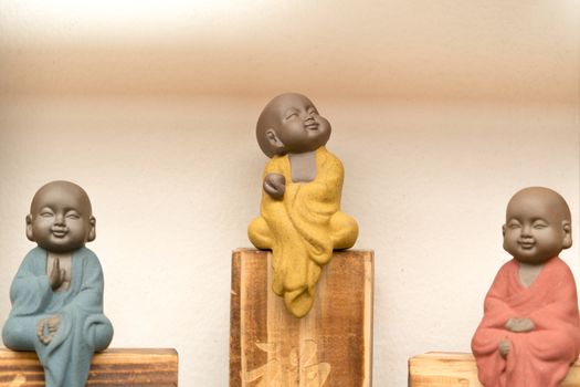 statue of little monk with colorful dress sitting on the wooden 