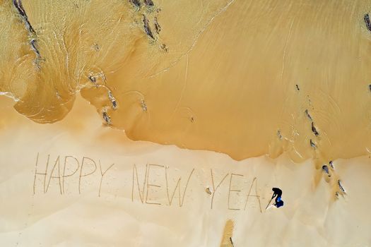 Aerial top shot from ocean waves and handwritten Happy New Year 