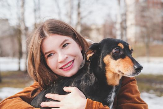 Human being happy with a dog. Loving pets concept: happy young woman hugs her dachshund at a walk
