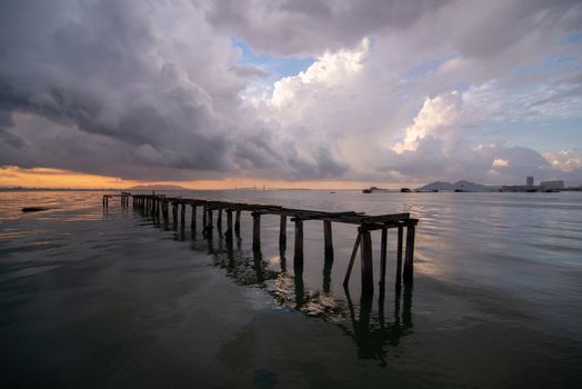 Wooden bridge at sea with Penang Bridge at background in majestic cloudy morning,