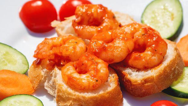 Mediterranean cuisine - freshly cooked shrimps on bread with vegetables. Seafood with cucumbers and tomatoes.