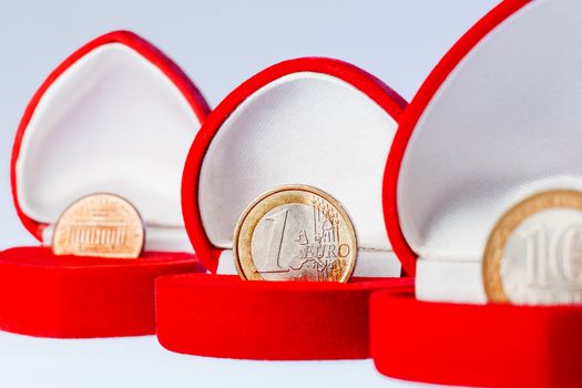 Red gift boxes with one euro, ten roubles and one cent coins. Focus on euro coin, the official currency of the eurozone (European Union).