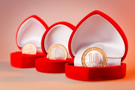 Red gift boxes with one euro, ten roubles and one cent coins. Focus on rouble coin, the official currency of Russian Federation.