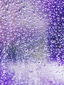 Rain drops on glass. Silhouettes of violet water drops on a transparent surface.